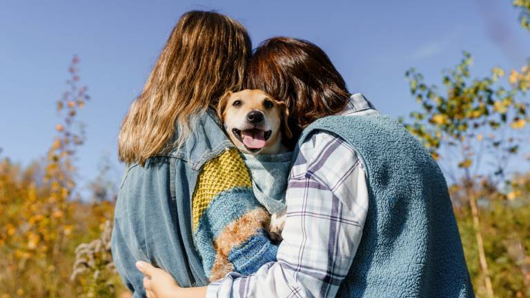 Zwei Frauen umarmen sich und einen Hund
