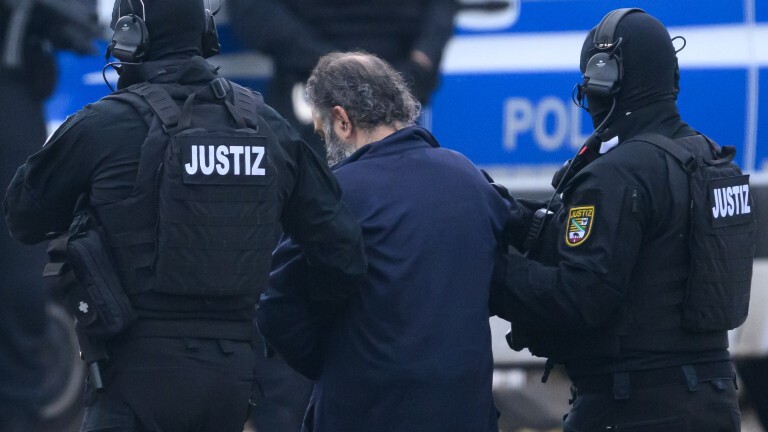Der mutmaßliche Attentäter des Anschlags auf den Magdeburger Weihnachtsmarkt im Dezember 2024 wird von Justizpersonal zu einer Fahrzeugkolonne geführt.
