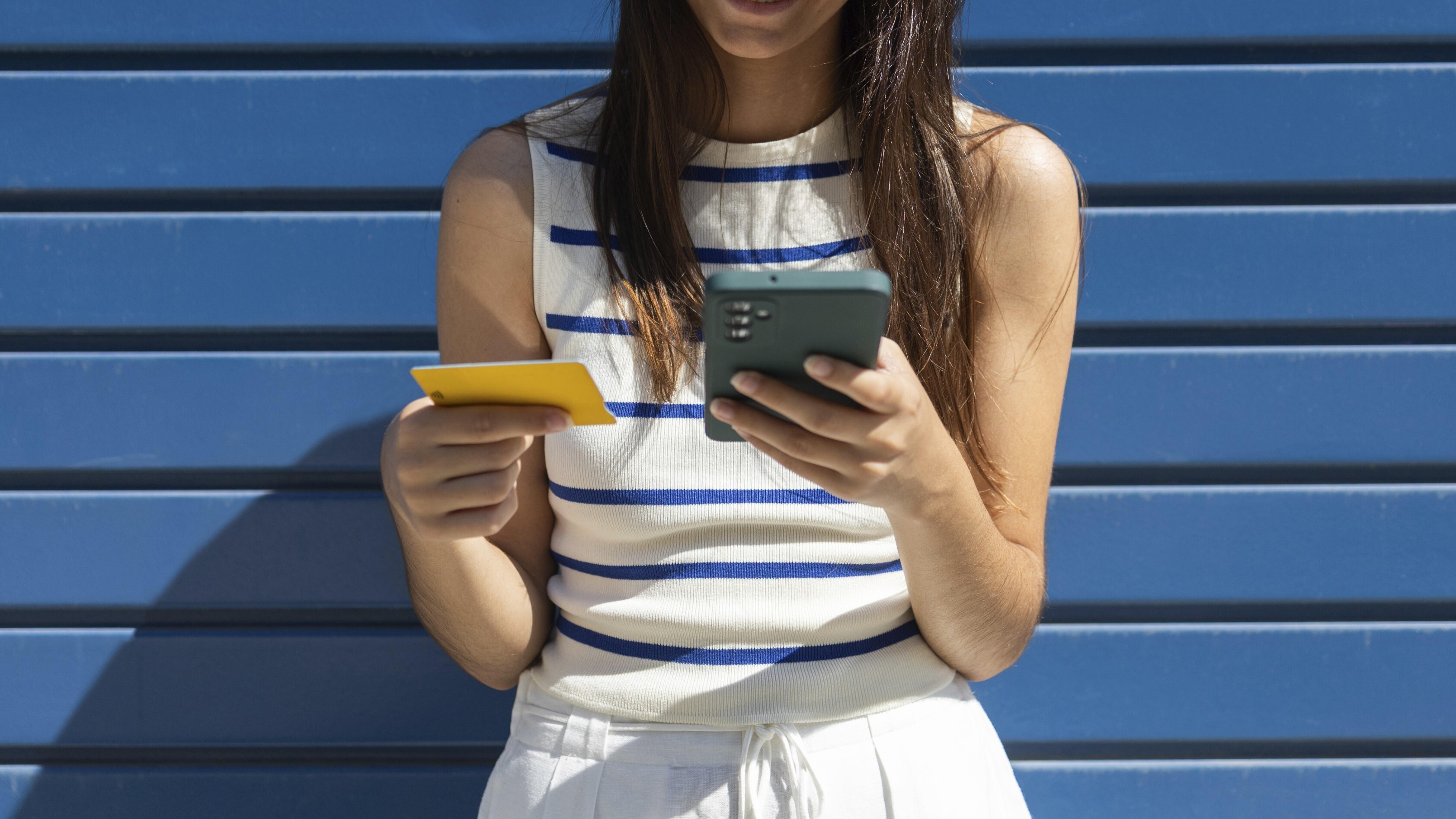 Eine Frau hält Kreditkarte und Smartphone in der Hand.