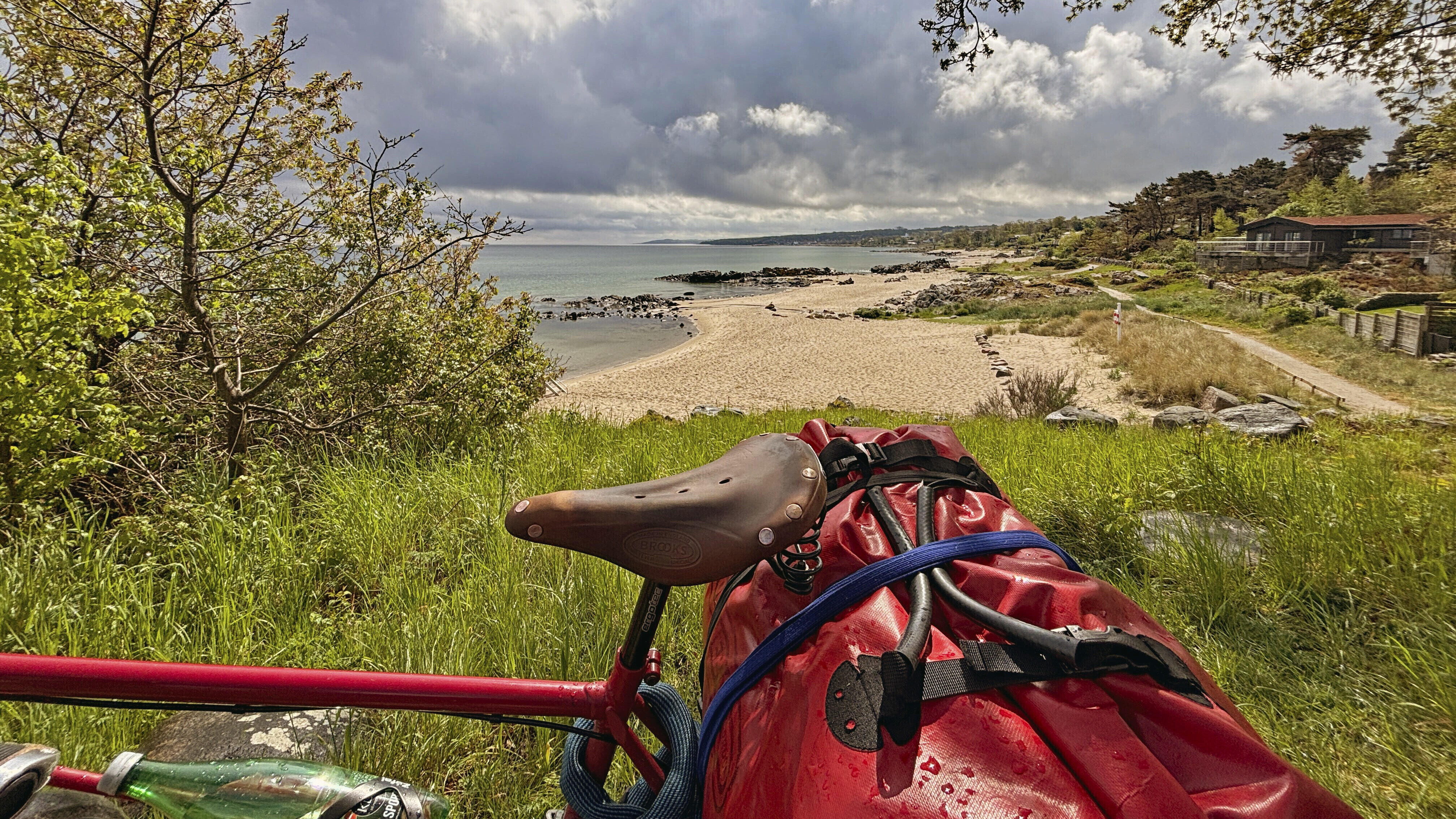 Fahrrad steht auf einem Hügel mit Blick auf Sandstrand und Meer