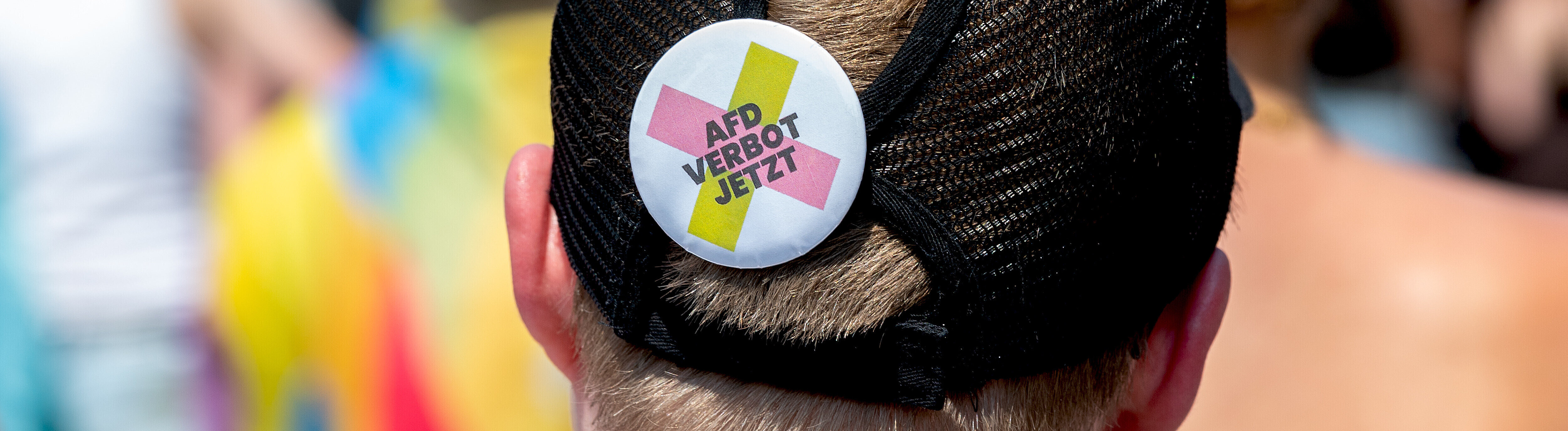 Teilnehmende Person beim Christopher Street Day (CSD) in Schleswig trägt Ansteck-Pin auf Cappy, auf dem „AfD Verbot jetzt“ steht (27.06.2026)