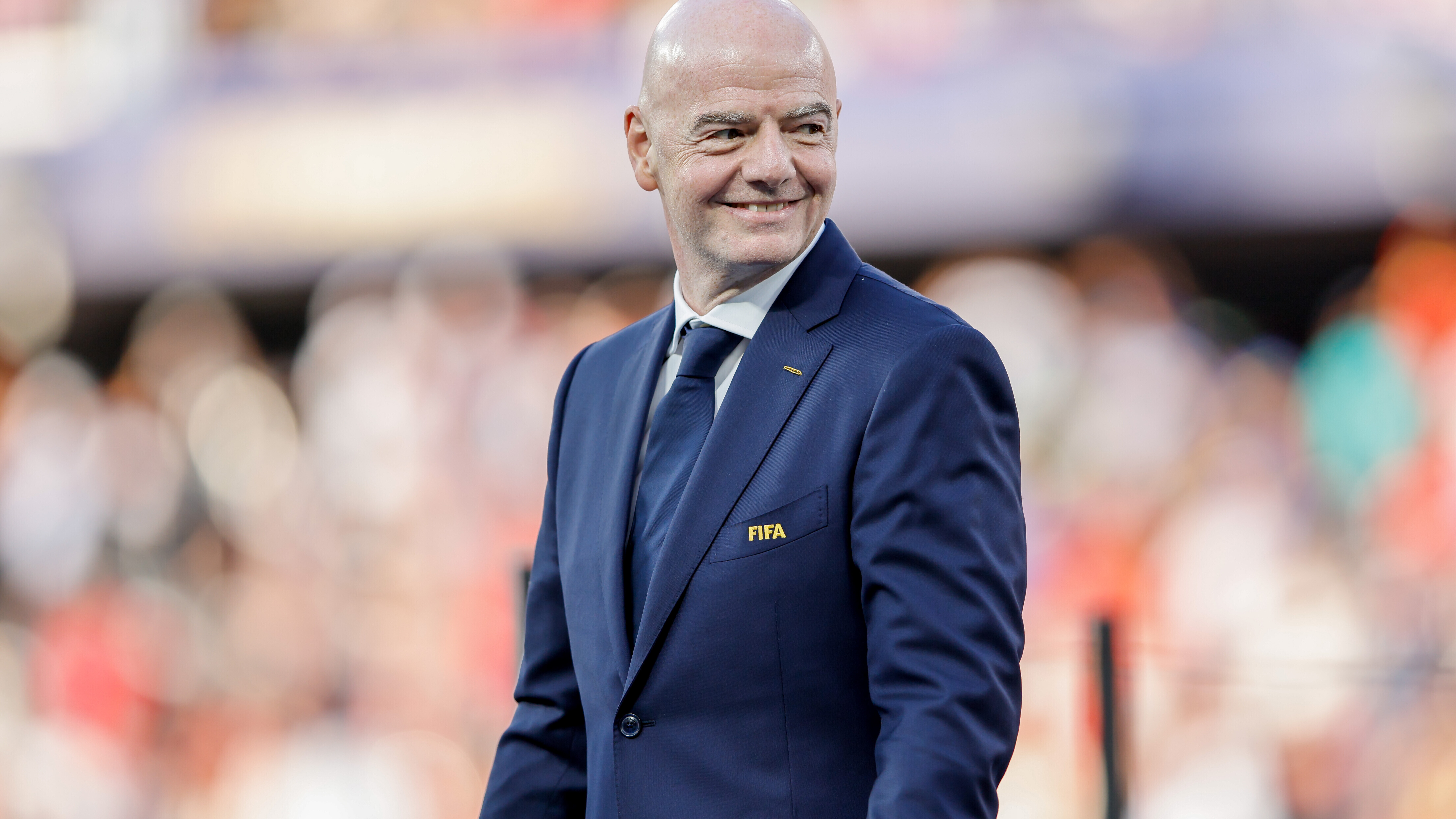 FIFA-Präsident Gianni Infantino läuft über das Fußballfeld beim WM-Spiel Spanien gegen Argentinien und lächelt.