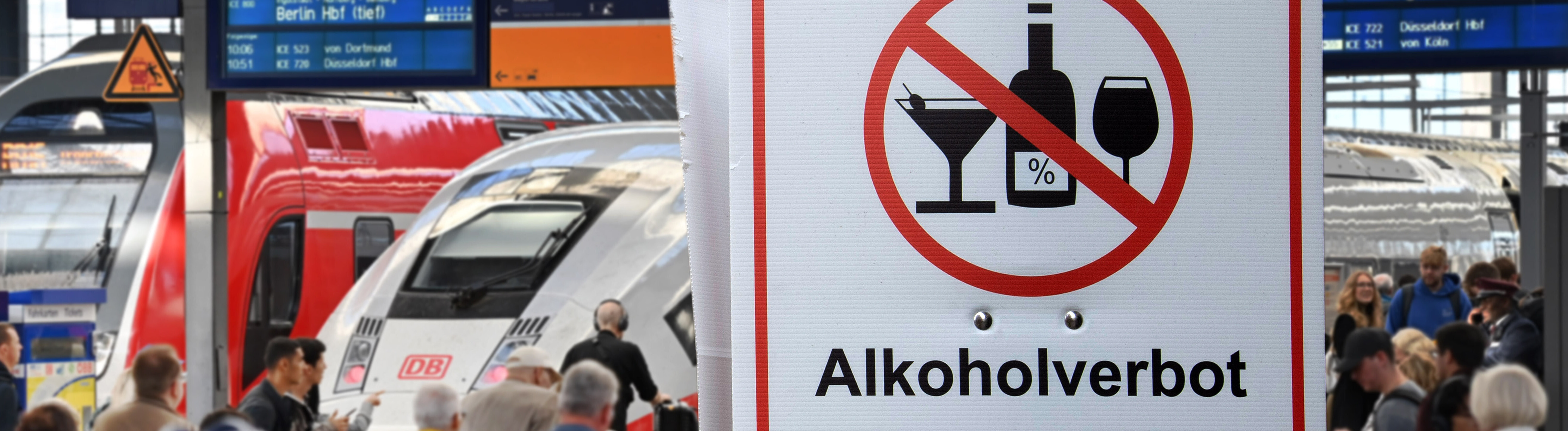 Fotomontage: Menschen in einem Bahnhof, großes Schild „Alkoholverbot 0-24h“ / Die Deutsche Bahn will kuenftig an allen Bahnhoefen ein Alkoholverbot durchsetzen.