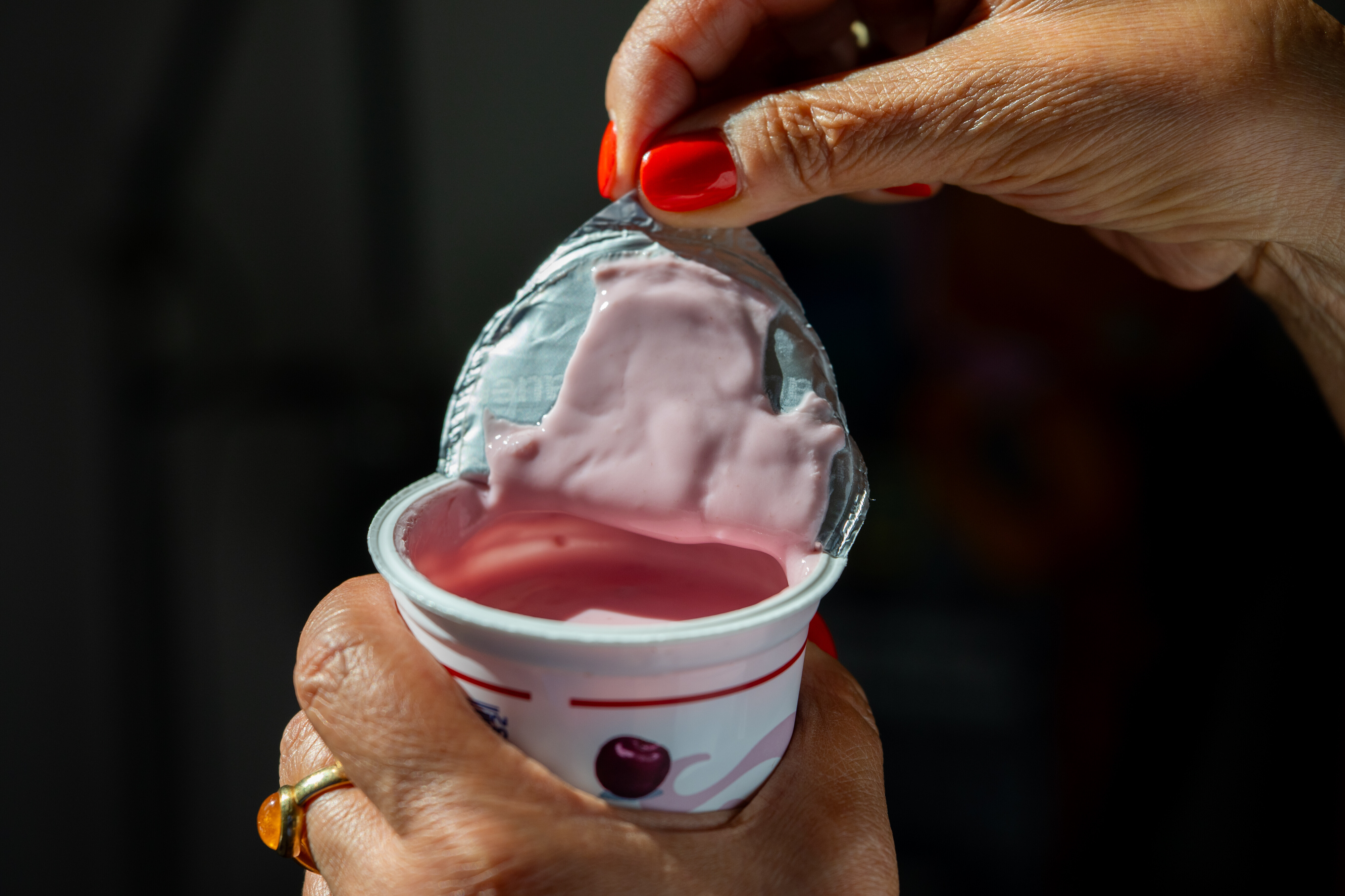 Eine Frau oeffnet am 28.07.2026 in Berlin einen Becher Kirschjoghurt.