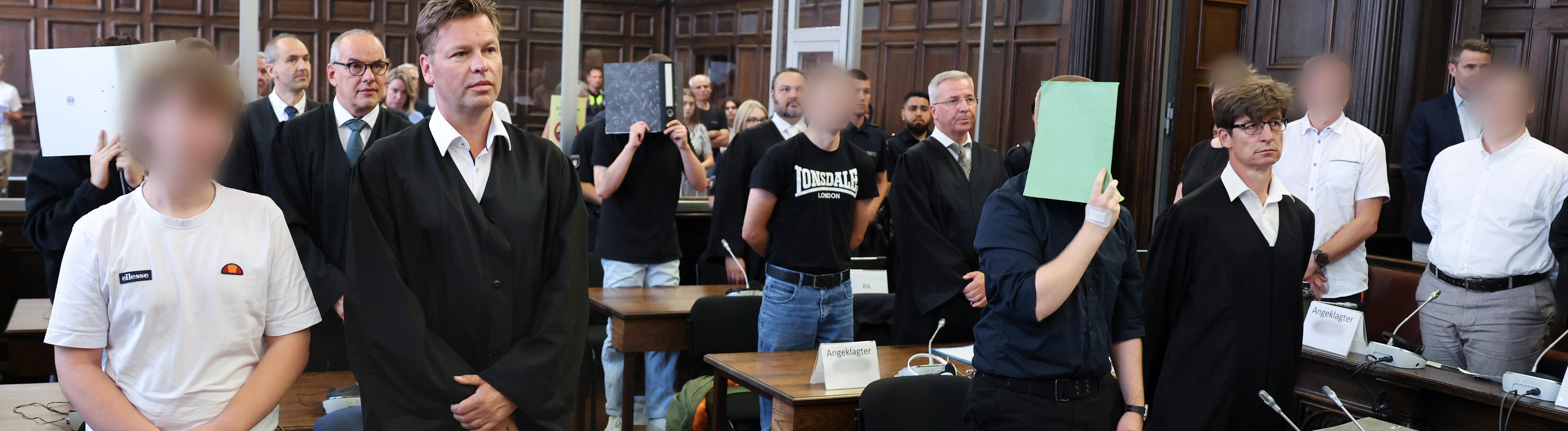 Sieben Angeklagte stehen mit ihren Verteidigern im Sitzungssaal im Hamburger Strafjustizgebäude zu Beginn des Prozesses gegen die rechtsextreme Terrorgruppe „Letzte Verteidigungswelle“.