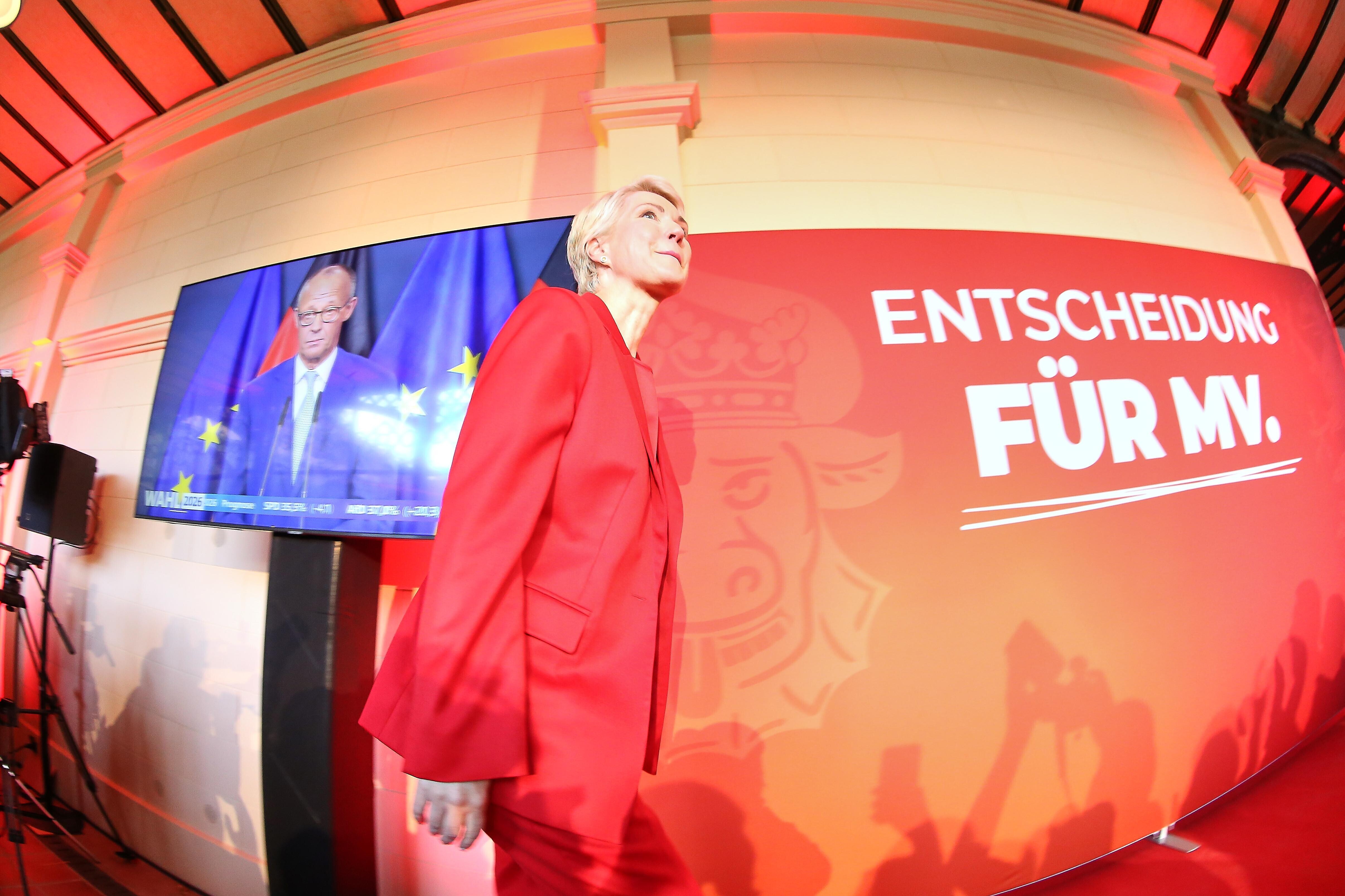 Landtagswahl in Mecklenburg-Vorpommern 2026: Manuela Schwesig läuft auf der SPD-Wahlparty an einem Monitor vorbei, auf dem Bundeskanzler Merz zu sehen ist.