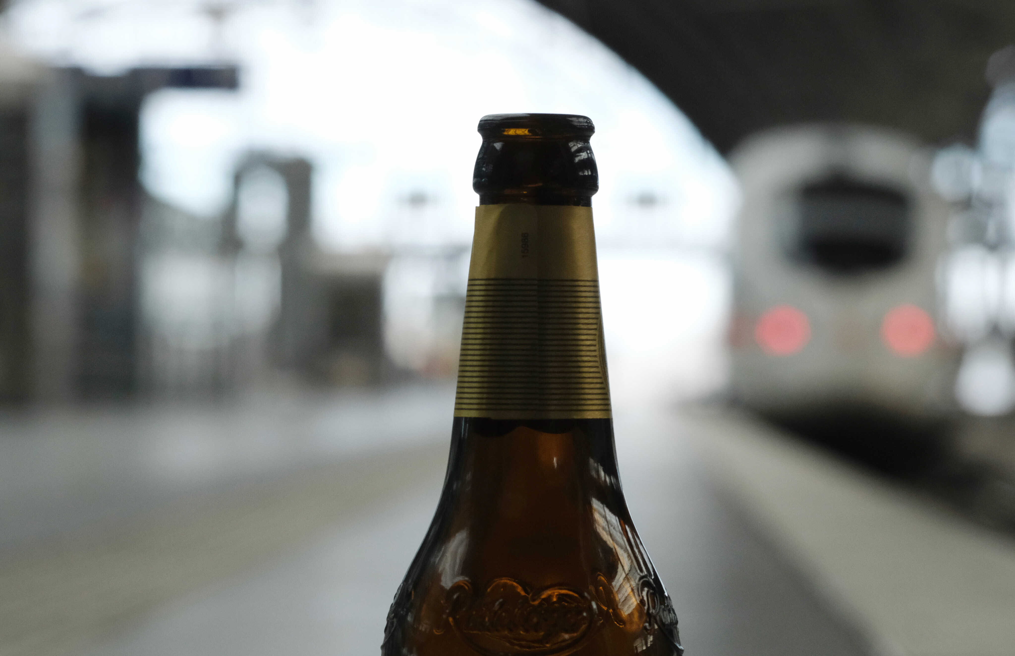 Eine leere Flasche Bier steht an einem Bahnsteig