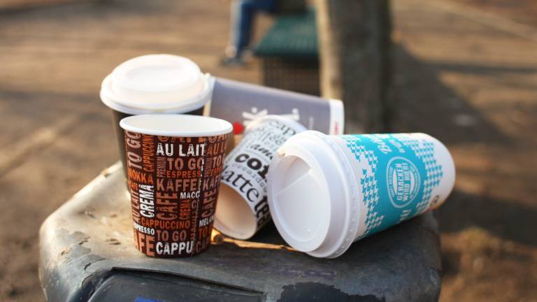 Einwegbecher stapeln sich auf einem Mülleimer.