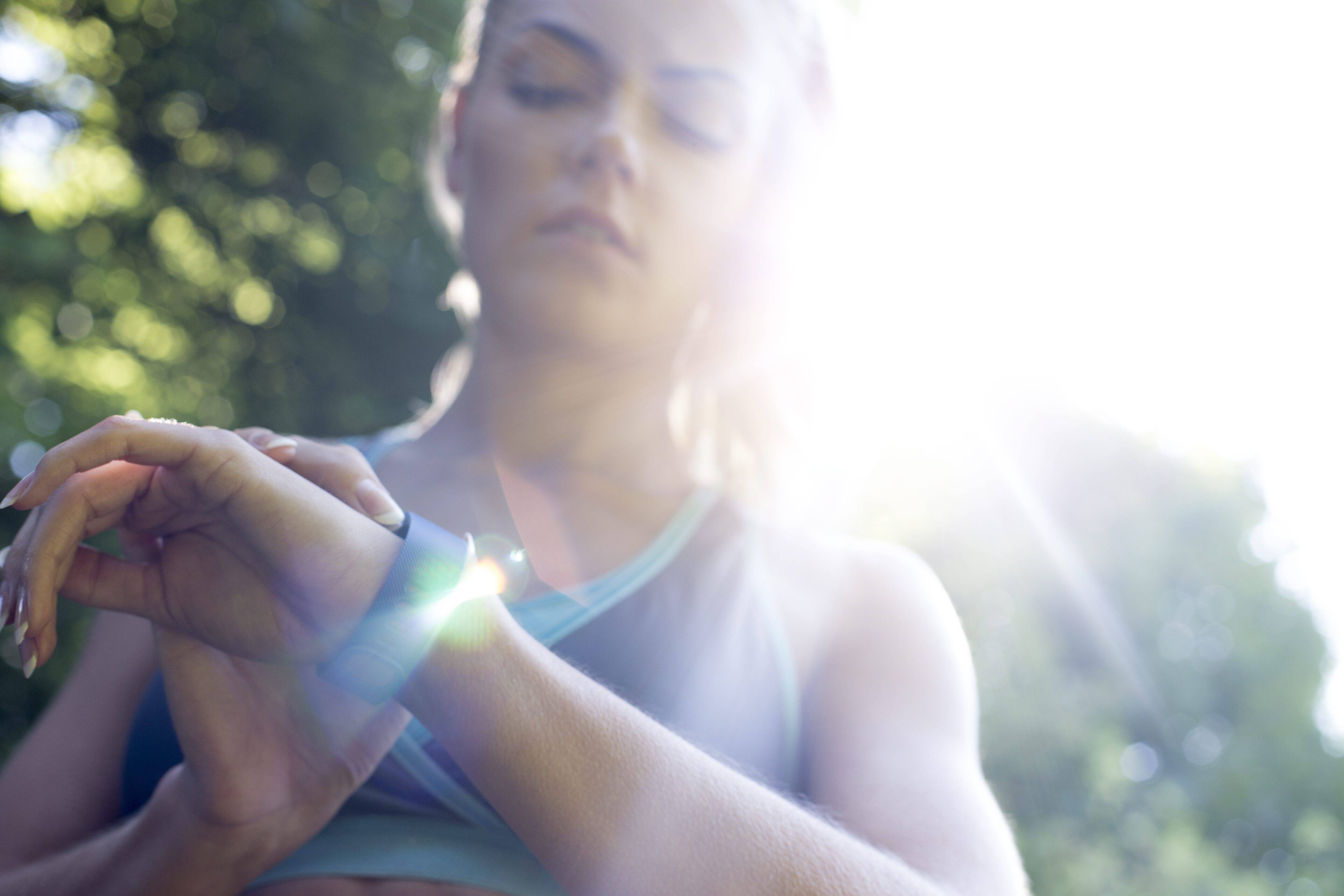 Eine junge Frau schaut auf ihren Fitnesstracker