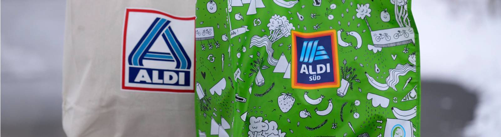 Person trägt Einkaufstaschen von Aldi-Süd (r.) und Aldi-Nord