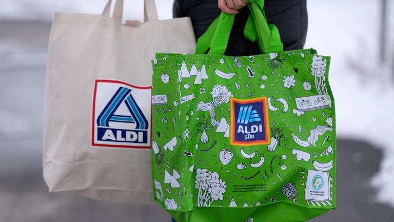 Person trägt Einkaufstaschen von Aldi-Süd (r.) und Aldi-Nord