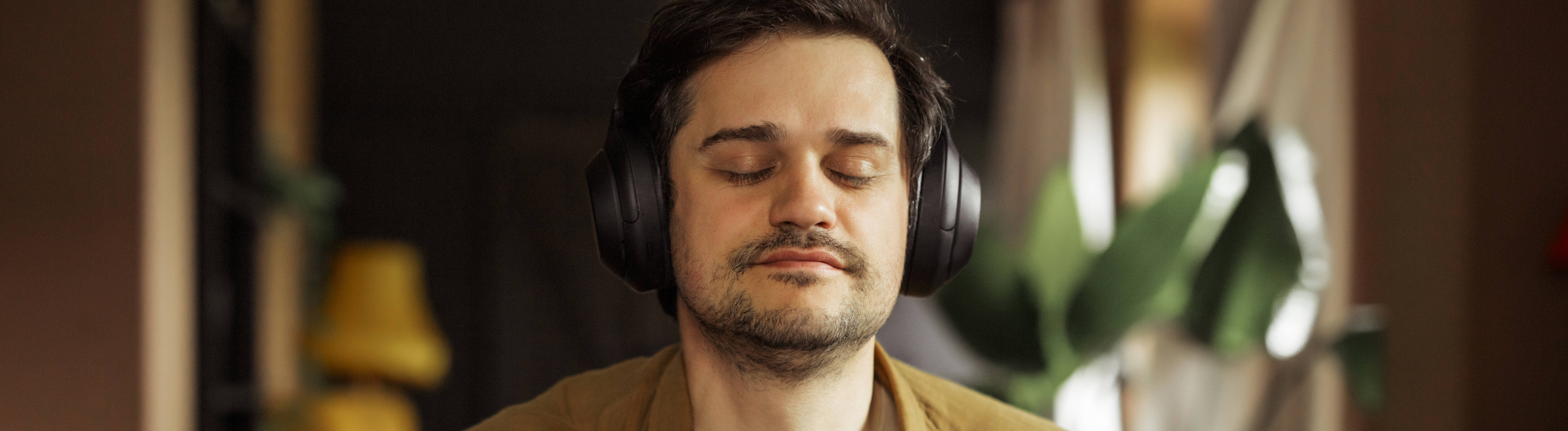 Ein Mann sitzt an einem Keyboard und trägt dabei Kopfhörer. Sein Augen sind geschlossen.
