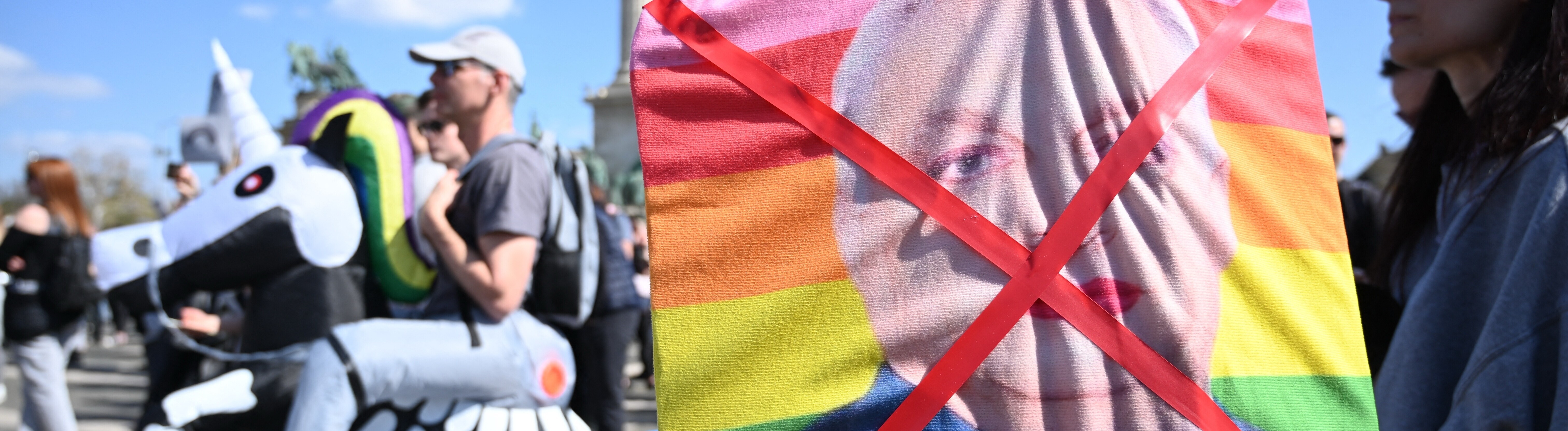 Demonstrantin hält durchgestrichenes Bild mit geschminkten ungarischen Premierministers Viktor Orban auf einer Regenbogenfahne (12.4.2025)
