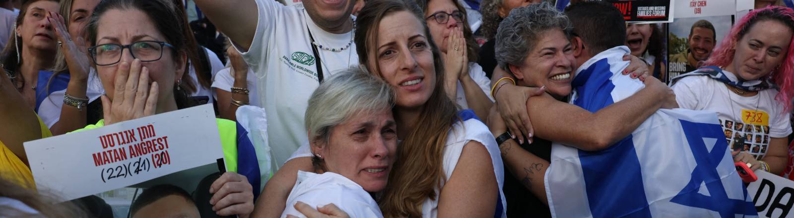 Menschen halten Israel-Flaggen in die Höhe und umarmen sich auf dem Platz der Geiseln in Tel Aviv, Israel (13.10.2025)