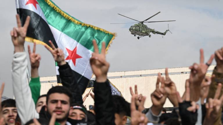 Ein Hubschrauber fliegt über eine Menschenmenge. Das Siegeszeichen und Flaggen werden gezeigt.  Es handelt sich um Feierlichkeiten zum Jahrestag des Sturzes des Machthabers Baschar al-Assad in der syrischen Hauptstadt Damaskus (8.12.2025, Syrien)