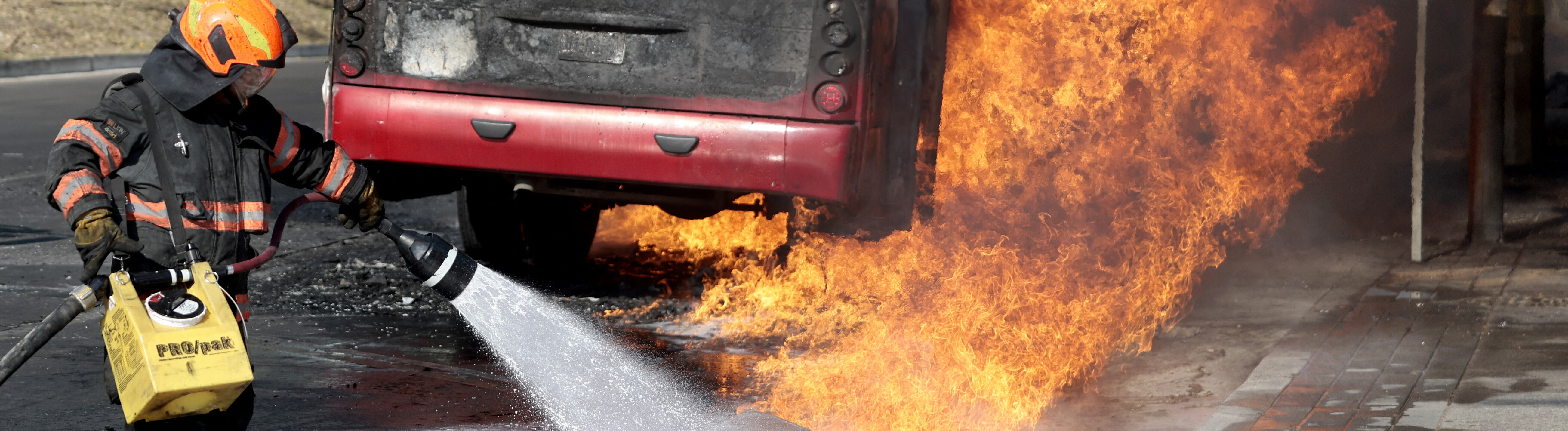 Einsatzkraft der Feuerwehr löscht auf einer Hauptstraße in Zapopan einen brennenden Bus (Mexiko, 22.02.2026)