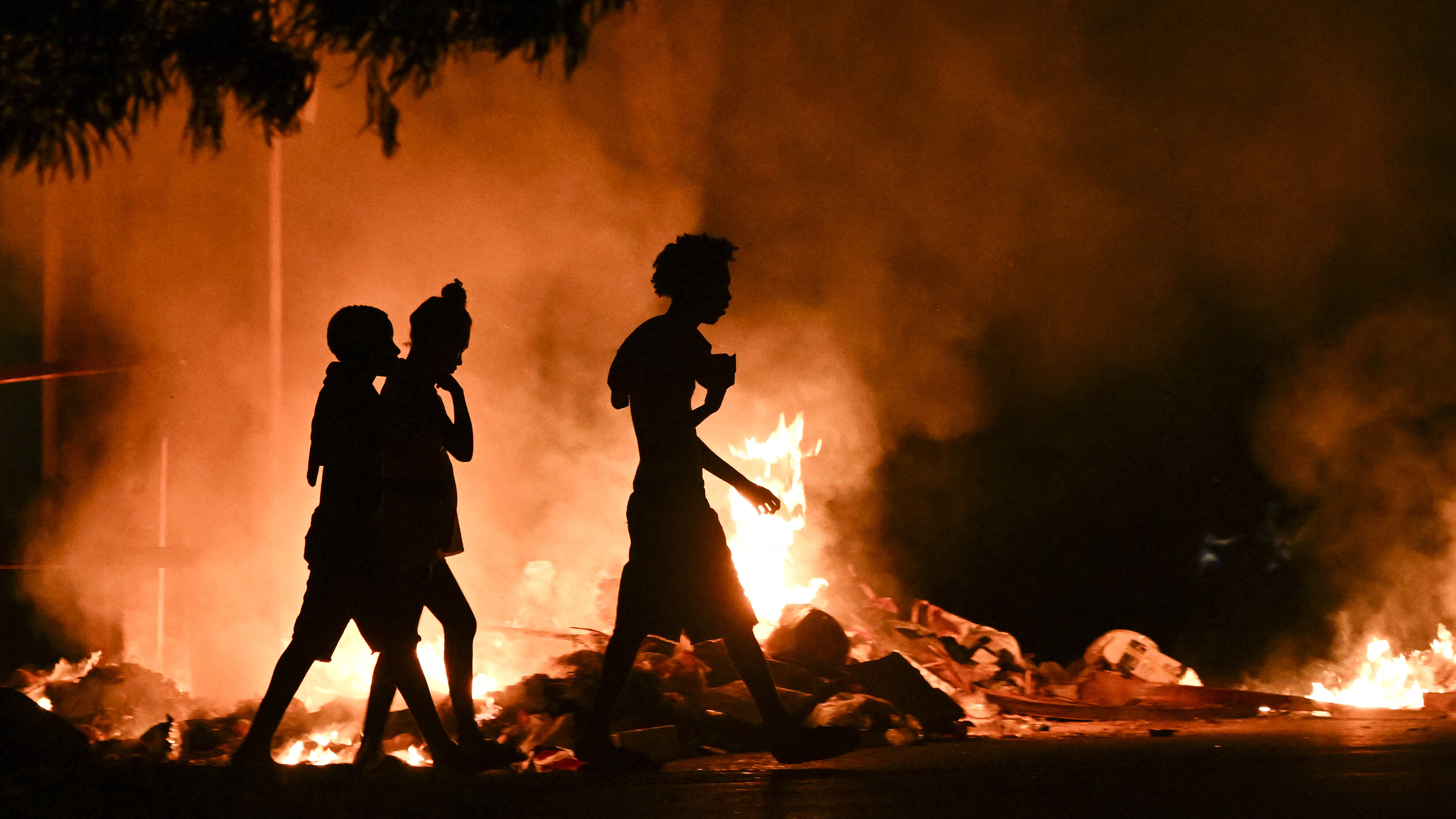 Kubaner gehen an einem Feuer vorbei, das von Demonstranten während eines Protests gegen den Mangel an Energie und Stromausfälle im Viertel Lawton in Havanna am 14. Mai 2026 gelegt wurde.