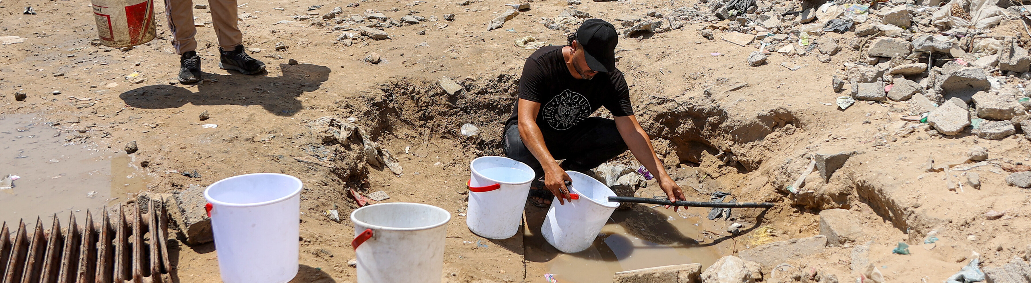 Ein Mann füllt Eimer mit Wasser, das aus den Restbeständen unterirdischer Leitungen in einem Lager für Kriegsvertriebene im Stadtviertel Sheikh Radwan in Gaza-Stadt geschöpft wird (06.07.2026)