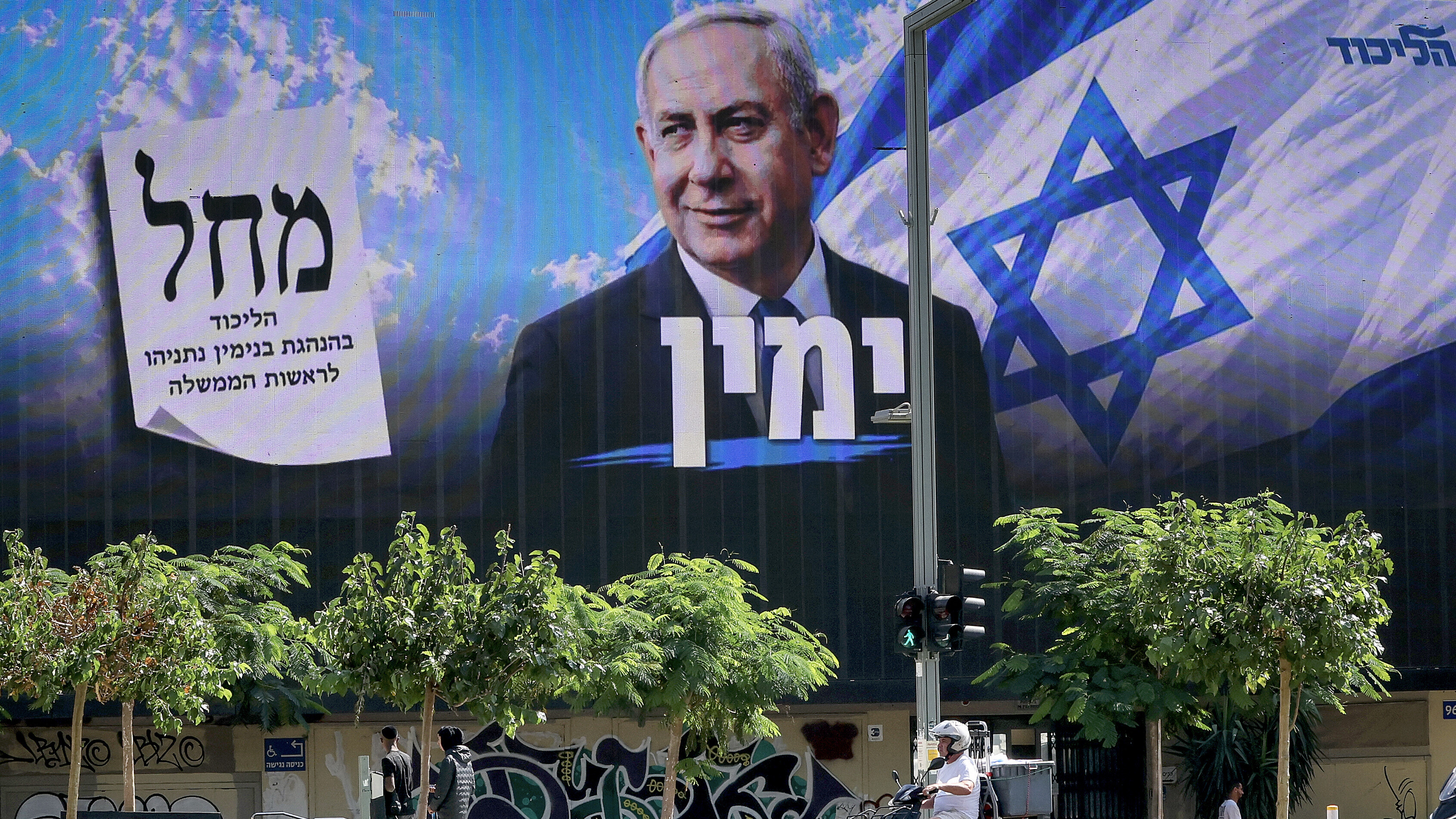 Ein Motorroller fährt an einer Plakatwand vorbei, auf der Israels Premierminister Benjamin Netanjahu von der Likud-Partei zu sehen (20.10.2026, Tel Aviv, Israel)