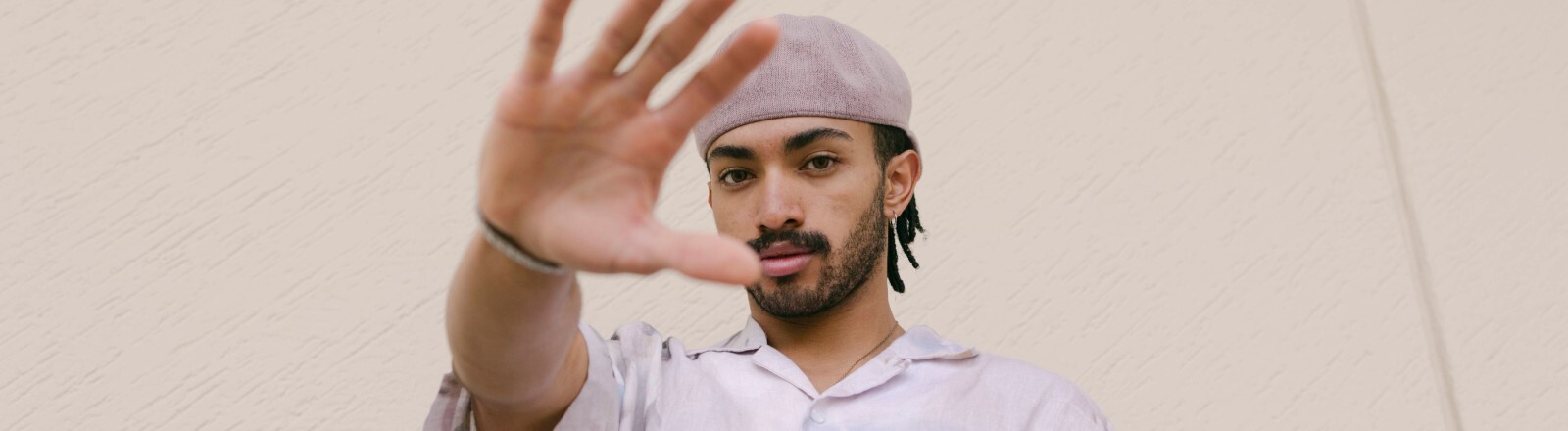 Ein Mann schaut in die Kamera und hält dabei seine ausgestreckte Hand vor sich.