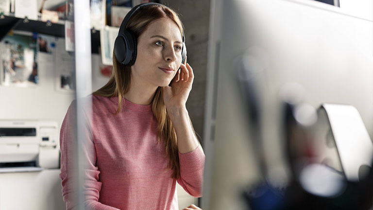 Eine junge Frau arbeitet fröhlich im Homeoffice.