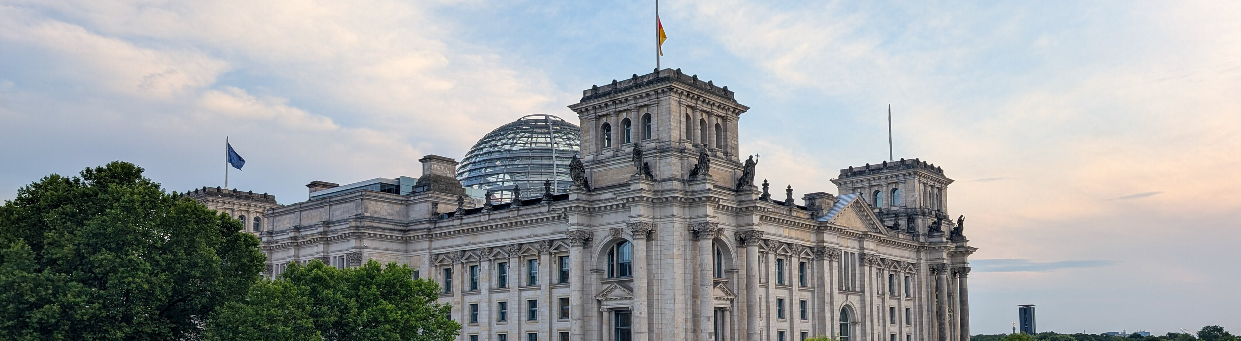 Das Reichstagsgebäude mit der Glaskuppel von der Seite. Davor ist die Spree zu sehen.