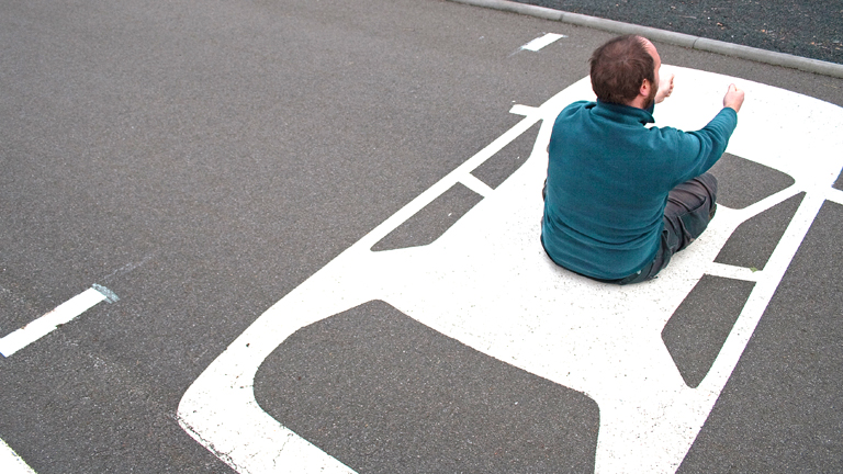 Mann sitzt auf Parkplatz