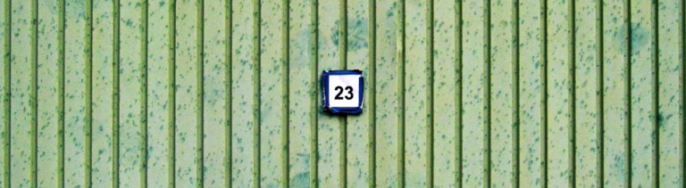 Auf einer grünen Wand hängt ein Schild, auf dem 23 steht.