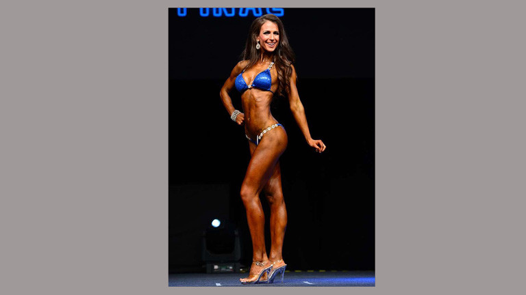 Kathrin Weishaupt bei einem Wettbewerb. Sie trägt einen blauen Bikini und silberne High Heels.