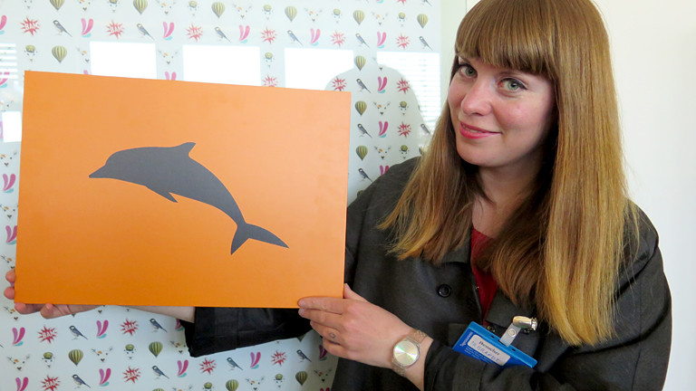 Frau mit einem Delphin-Schild in der Hand.