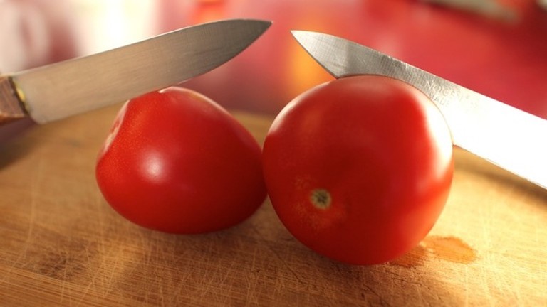 Zwei Messer schneiden zwei Tomaten.