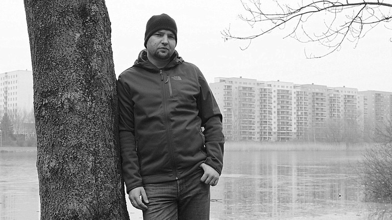 Porträt von Sebastian Caspar, im Hintergrund eine Plattenbau-Siedlung.