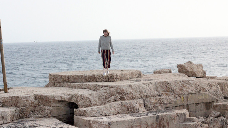 Eine Frau auf Klippen vor dem Meer.