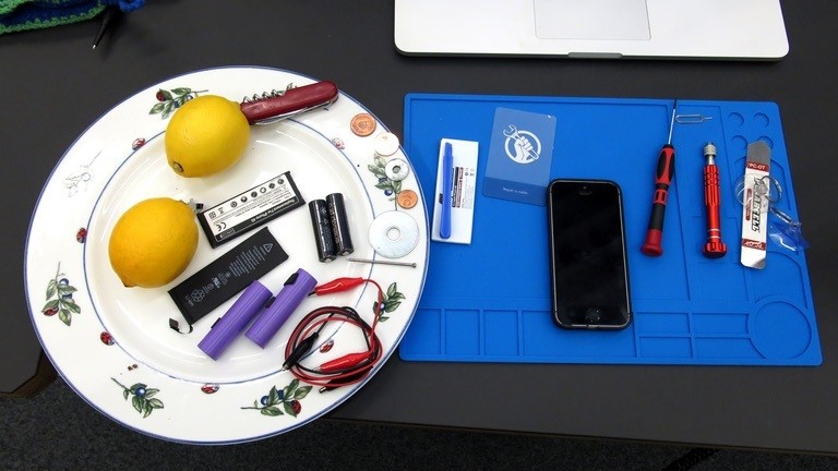 Ein Smartphone und diverse Werkzeuge liegen auf einem Tisch.