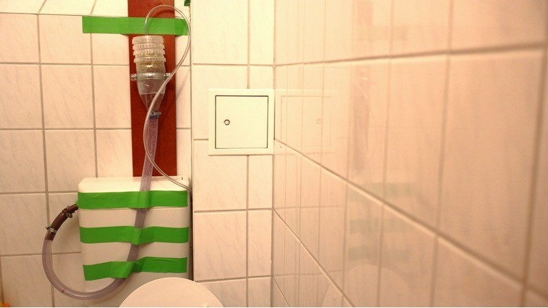 Die fertige Konstruktion zu Hause im Badezimmer. Das Wasser fließt über den kleinen Schlauch in den Sprossenturm - und über das improvisierte Siphon des großen Schlauchs zurück in den Spülkasten.