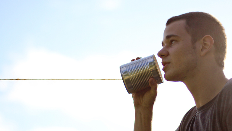 Ein Mann spricht in ein Dosentelefon