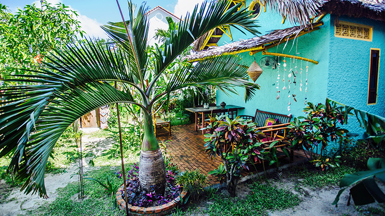 Blick auf das Hostel Happy Bird mit Garten. Es sieht sehr gemütlich aus.