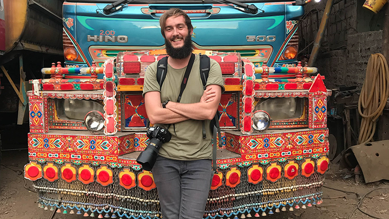 Clemens Sehi posiert vor einem bunten Bus in Pakistan.