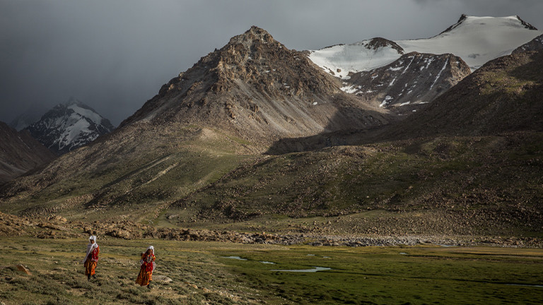 Zwei Frauen vor einer schroffen Berglandschaft in Pamir.