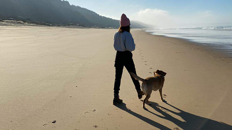Sarah Richmond geht mit ihrem Hund an einem unberührten Strand spazieren.