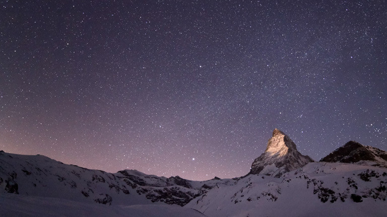 Der aufgehende Mond beleuchtet die Spitze des Matterhorns.