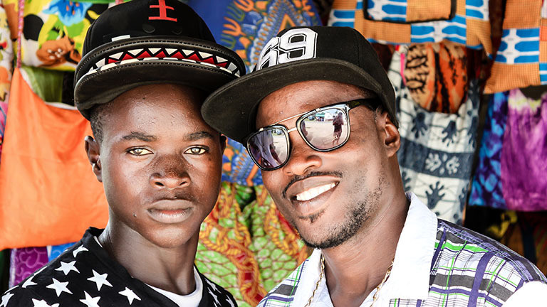 Zwei junge Männer stehen nebeneinander und lächeln, Ghana.