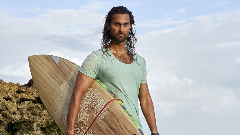 Afridun Amu mit einem Surfbrett unter dem Arm.