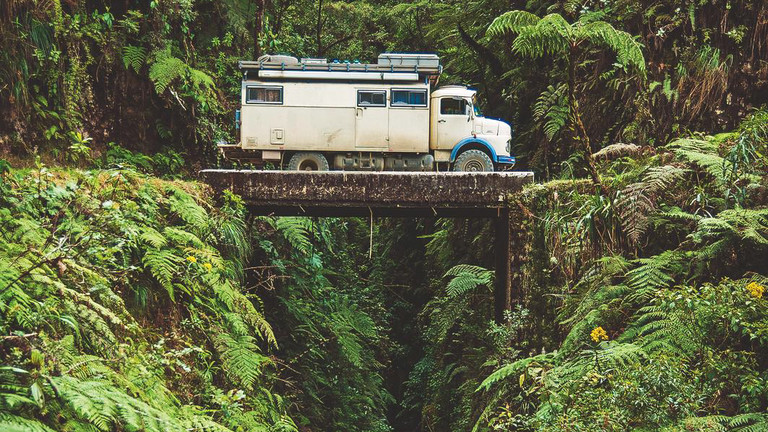Ein Oldtimer-LKW auf einer winzigen Brücke über einer Schlucht in Bolivien.