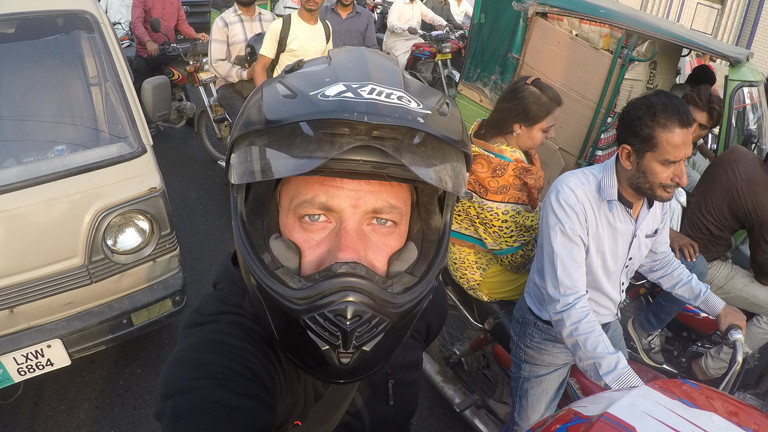 Mann mit Motorrad auf Straße mit Menschen