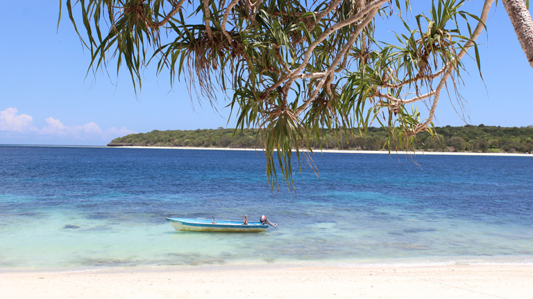 Strand, Sand und ein kleiner Boot im Meer.