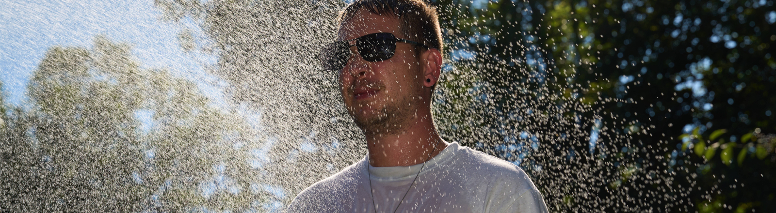 Ein Mann kühlt sich im Wassernebel ab