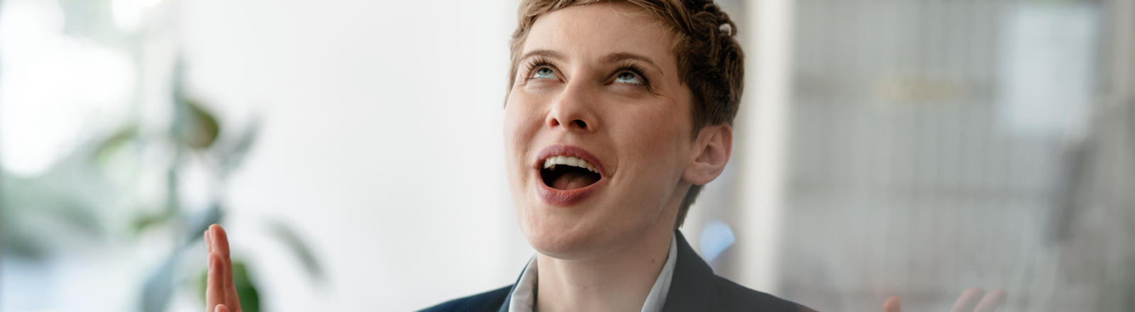 Eine Business-Frau blickt nach oben und wirft die Hände in die Höhe