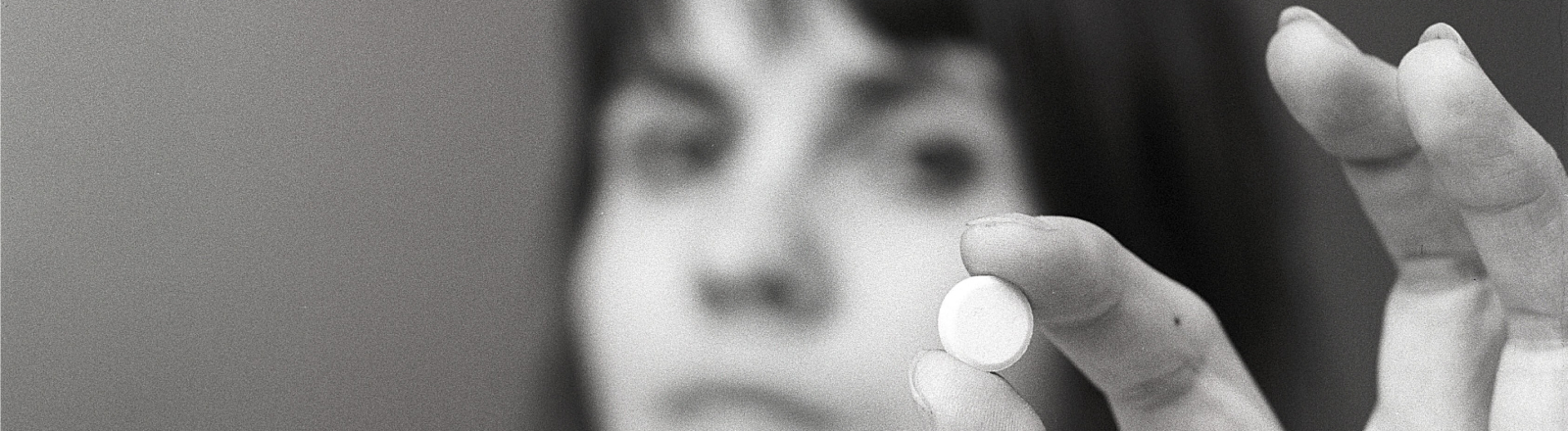 Eine Frau hält eine weiße Pille zwischen ihren Fingern. Eine Illustration für die Einnahme von Medikamenten oder für Antibabypillen zu dieser Zeit. Schweden 1971