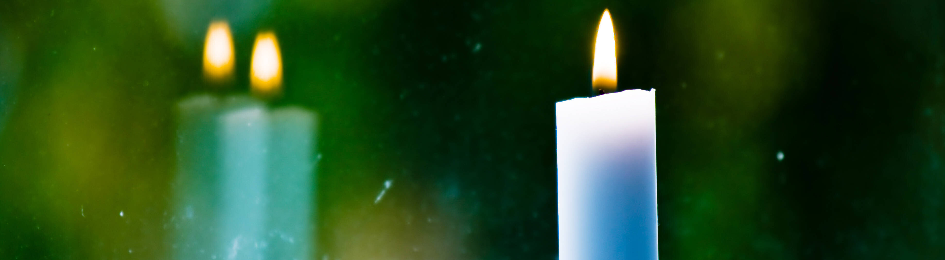 Eine brennende Kerze steht an einem Fenster